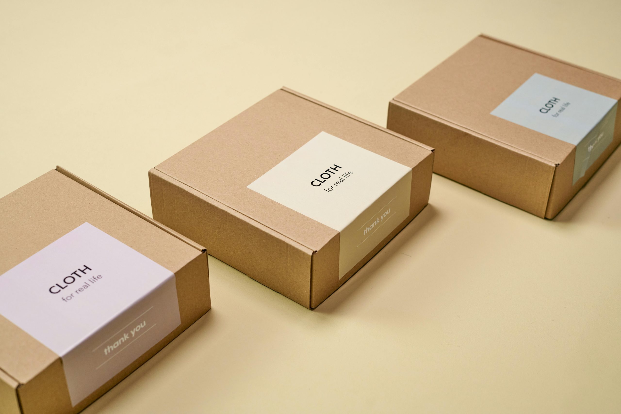 Brown kraft paper mailing boxes with custom branded stickers, demonstrating full-service private label packaging options for fashion startups.