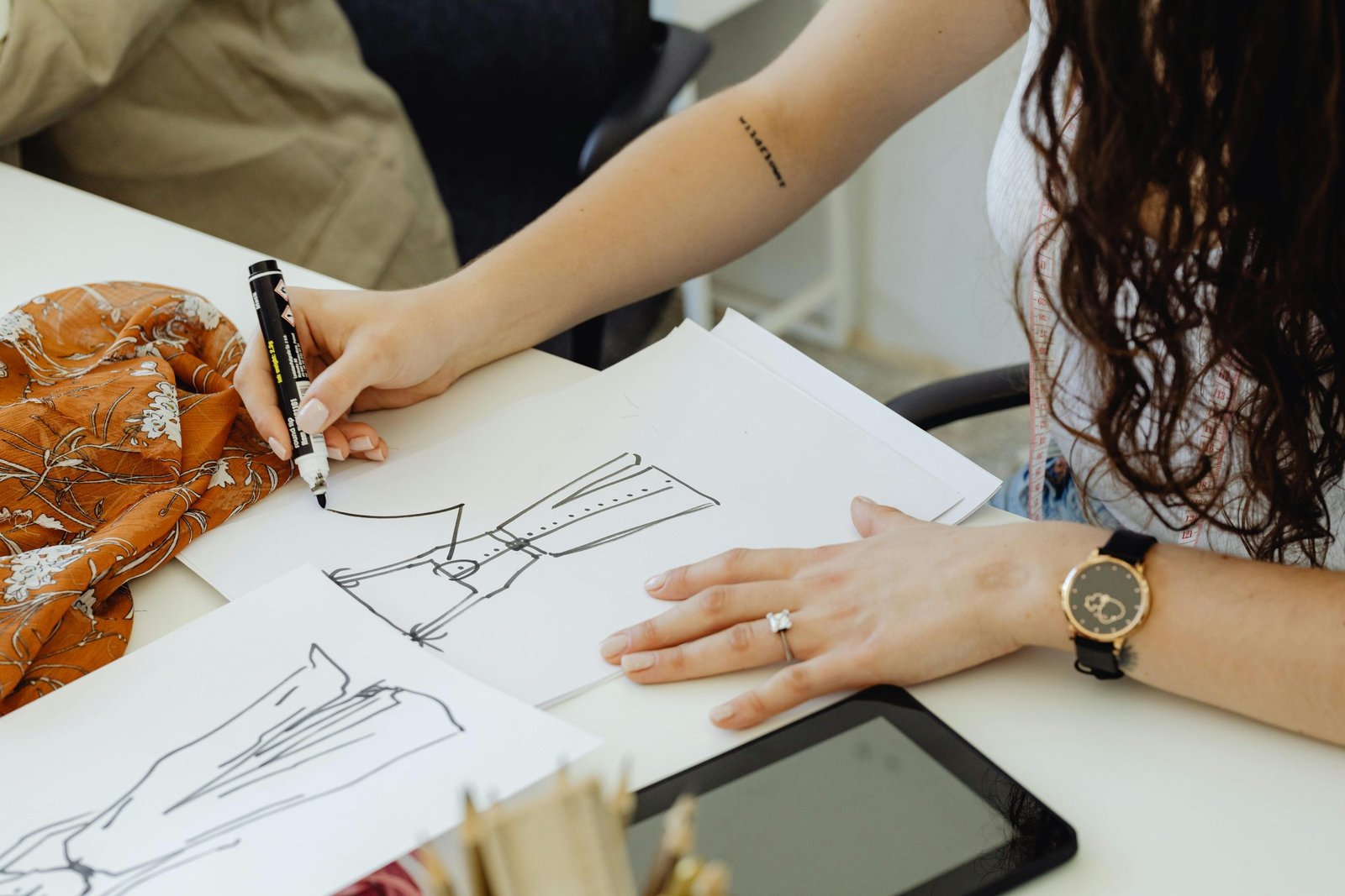 Fashion designer creating sketches to assist clients with tech pack development.