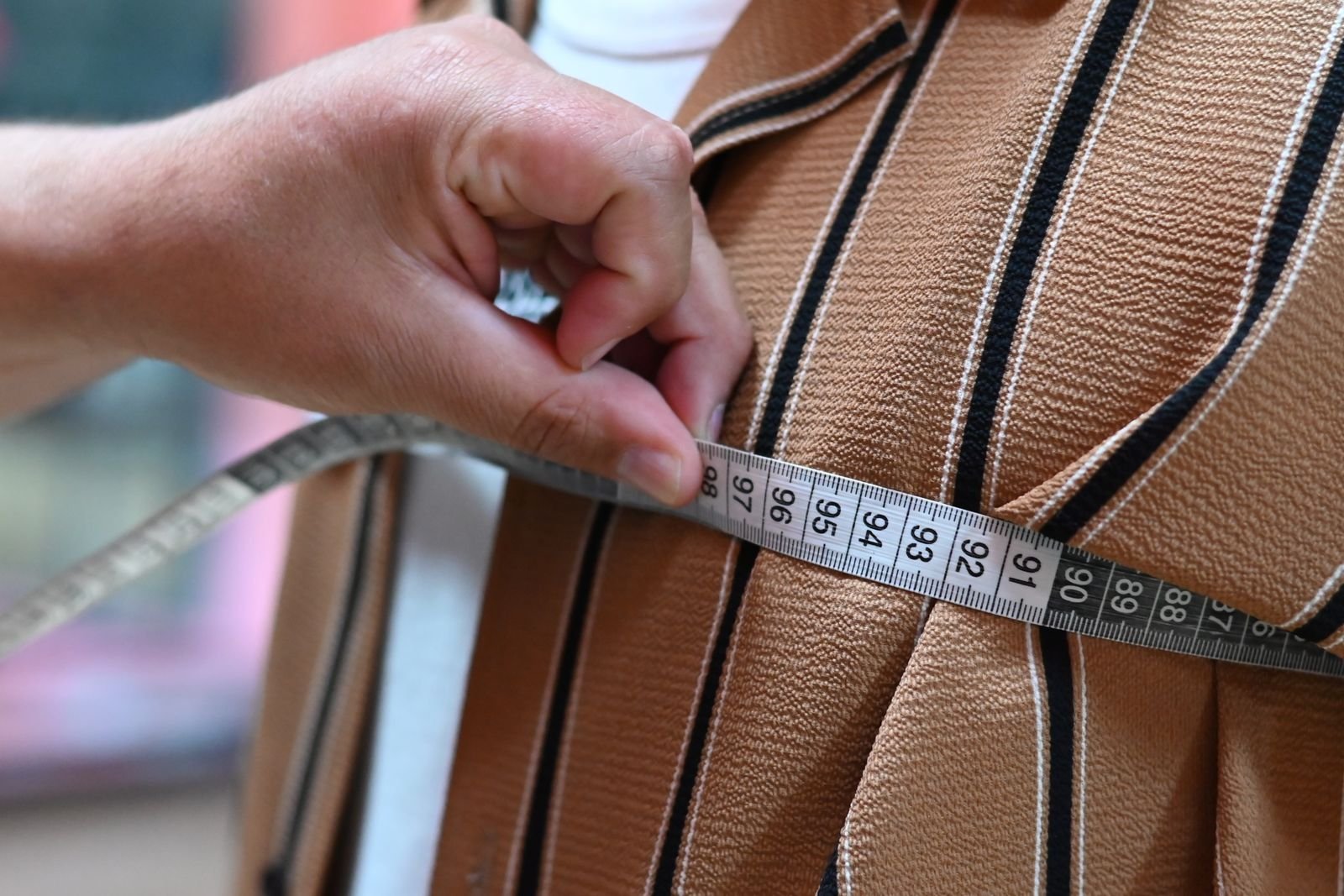 Tailor measuring fabric with a tape for garment shrinkage testing